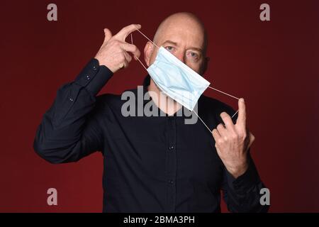 Mann, der die medizinische Maske richtig abzieht, Stockfoto