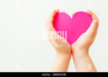 Nahaufnahme der Hände des Kindes, die Papier rosa Herz auf weißem Hintergrund. Konzept der Liebe. Stockfoto