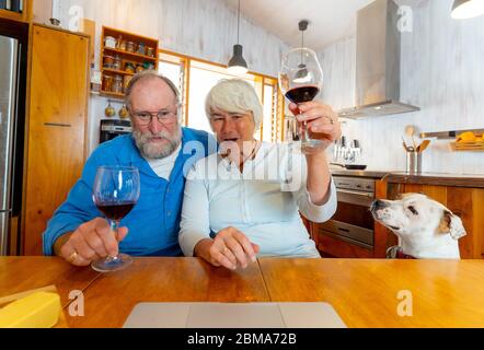 COVID-19 Bleiben Sie in Verbindung und hoffen Konzept. Happy Senior Paar mit Wein Video-Anruf Freunde auf dem Laptop oder Online-Chat mit der Familie feiern eas Stockfoto