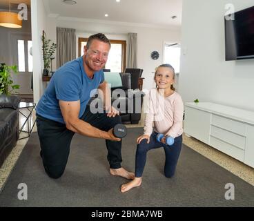 COVID-19-Abschaltung. Vater und Tochter in Quarantäne trainieren zusammen mit Hanteln. Vorteile der körperlichen Aktivität während des Sperrens. Bleiben Sie zu Hause, Stockfoto