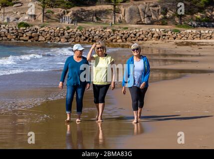 Schöne Gruppe von drei aktiven älteren Frau auf ihren 60ern zu Fuß, Sport und Spaß am Strand. Reife Frauen lachen genießen Spaziergang auf Vacat Stockfoto