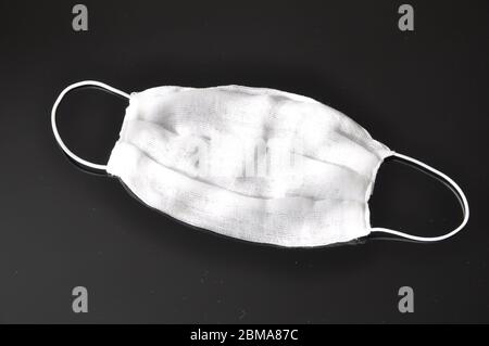 Gaze Bandagen mit elastischen Bändern über den Ohren, zu Hause gemacht, auf schwarzem Hintergrund. Atemschutz. Stockfoto