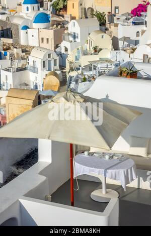 Griechenland. Sonniger Tag auf der Caldera der Insel Santorini. Tisch unter einem Sonnenschirm auf der Außenterrasse serviert Stockfoto