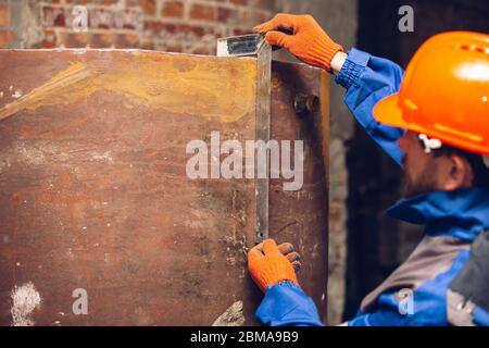 Nahaufnahme von Reparaturmann in Uniform, professionelle Baumeister mit Baumaschinen arbeiten. Prozess der Gebäude, Wohnung Renovierung, Reparatur, Gebäude Stockfoto