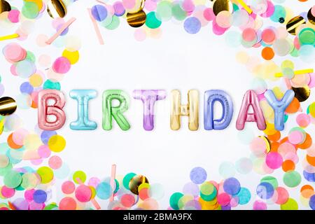 Word GEBURTSTAG aus bunten aufblasbaren Ballon Buchstaben in einem Rahmen aus bunten Konfetti auf weißem Hintergrund Stockfoto