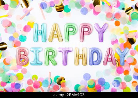 Nachricht HAPPY BIRTHDAY aus bunten aufblasbaren Ballon Buchstaben in einem Rahmen aus bunten Konfetti auf weißem Hintergrund Stockfoto