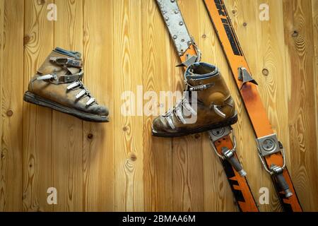 An einer Holzwand hängen klassische Ski- und Skiederstiefel. Sportgeräte des letzten Jahrhunderts Stockfoto