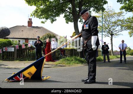 Ein Träger der Royal British Legion senkt seinen Standard in Bezug auf eine zweiminütige Stille in Redcar, North Yorkshire, zum 75. Jahrestag des VE Day. Stockfoto