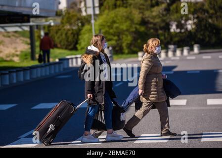 RIGA, LETTLAND. Mai 2020. Busarbeiter, die Schutzkleidung tragen und Gesichtsschutzmasken tragen, warten bei der Ankunft am internationalen Flughafen Riga auf die Passagiere. Stockfoto