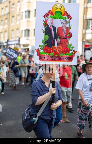 Eine Frau, die ein Schild mit einem Bild von Donald Trump und Theresa May und Text mit der Aufschrift "toxische Beziehung" bei einem Protest in London, 13. Juli 2018, hält Stockfoto