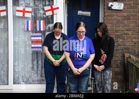 Michelle Martin, 58 (Mitte), ihre Tochter Emma Martin, 37 (links) und ihre Mieterin Sara Vottero, 33 (rechts), beobachten eine bundesweite zweiminütige Stille vor ihrem Haus in Bermondsey, London, anlässlich des 75. Jahrestages des Endes der Zweiten Welt in Europa, Tribut an Helden aus Vergangenheit und Gegenwart. Stockfoto