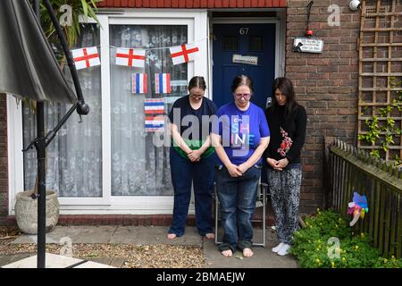 Michelle Martin, 58 (Mitte), ihre Tochter Emma Martin, 37 (links) und ihre Mieterin Sara Vottero, 33 (rechts), beobachten eine bundesweite zweiminütige Stille vor ihrem Haus in Bermondsey, London, anlässlich des 75. Jahrestages des Endes der Zweiten Welt in Europa, Tribut an Helden aus Vergangenheit und Gegenwart. Stockfoto