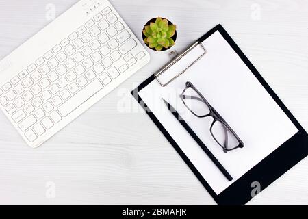 Geschäftskonzept. Arbeiten Sie von zu Hause aus. Büro-Flatlay mit weißer Tastatur, Lesebrille, Haustier und Notebook. Stockfoto