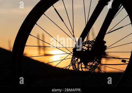 Profil eines Fahrradrades mit Scheibenbremsen bei Sonnenuntergang. Stockfoto