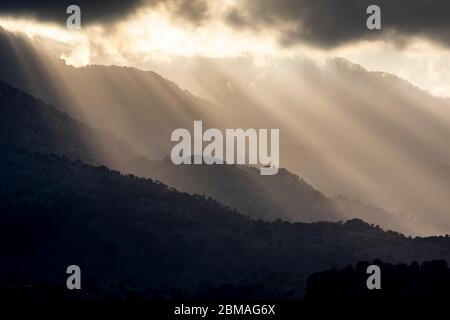 Sonnenstrahlen durchdringen dunkle Wolken über Bergen in Kreta, Griechenland Stockfoto