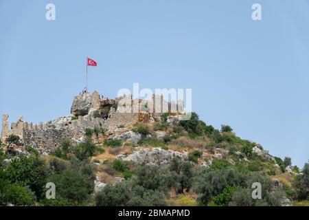 Kalekoy, Simena , Türkei - 03. Juni 2019: Kalekoy Dorf mit Steinhäusern und Burg auf dem Hügel in der Uchagiz Bucht in der Türkei in der Nähe versunkener Stadt Stockfoto