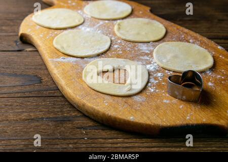 Herzförmige Knödel, Mehl auf Holzhintergrund. Kochknödel. Vorderansicht, Nahaufnahme Stockfoto