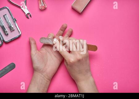 Überwucherten Nägel mit einem alten gesprungenen Gel-Politur. Selbstentfernung von altem Gel-Lack von den Nägeln mit einer Nagelfeile. Konzept der persönlichen Betreuung in der Schließung von Stockfoto