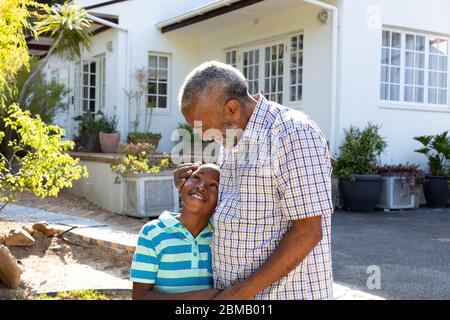 Ein älterer afroamerikanischer Mann und sein Enkel verbringen an einem sonnigen Tag Zeit zusammen in ihrem Garten Stockfoto