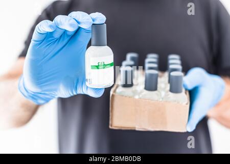 Handdesinfektionsmittel Hygiene Alkohol Gel Flaschen in den Händen des Mannes trägt Latex medizinische Handschuhe und Schutzmaske während Coronavirus COVID-19 Pandemien. Hea Stockfoto