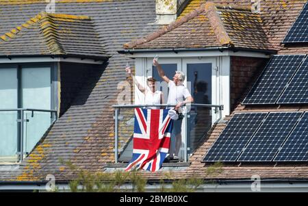 Littlehampton UK 8. Mai 2020 - EIN Paar auf seinem Balkon in Ferring bei Worthing erhebt ein Glas zum Gedenken an den Jahrestag des VE Day während der Sperrbeschränkungen der COVID-19-Pandemie. Es ist 75 Jahre her, dass der Sieg in Europa über die Deutschen während des Zweiten Weltkriegs verkündet wurde : Credit Simon Dack / Alamy Live News Stockfoto