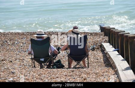 Littlehampton UK 8. Mai 2020 - Menschen versammeln sich am Strand von Ferring bei Worthing, um zu beobachten, wie die spitfire in der Ferne vorbeifliegen, um an den Jahrestag des VE-Tages während der Sperrbeschränkungen der COVID-19-Pandemie zu erinnern. Es ist 75 Jahre her, dass der Sieg in Europa über die Deutschen während des Zweiten Weltkriegs verkündet wurde : Credit Simon Dack / Alamy Live News Stockfoto