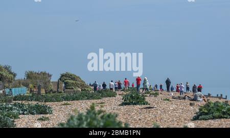 Littlehampton UK 8. Mai 2020 - Menschen versammeln sich am Strand von Ferring bei Worthing, um zu beobachten, wie die spitfire in der Ferne vorbeifliegen, um an den Jahrestag des VE-Tages während der Sperrbeschränkungen der COVID-19-Pandemie zu erinnern. Es ist 75 Jahre her, dass der Sieg in Europa über die Deutschen während des Zweiten Weltkriegs verkündet wurde : Credit Simon Dack / Alamy Live News Stockfoto
