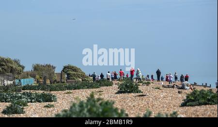 Littlehampton UK 8. Mai 2020 - Menschen versammeln sich am Strand von Ferring bei Worthing, um zu beobachten, wie die spitfire in der Ferne vorbeifliegen, um an den Jahrestag des VE-Tages während der Sperrbeschränkungen der COVID-19-Pandemie zu erinnern. Es ist 75 Jahre her, dass der Sieg in Europa über die Deutschen während des Zweiten Weltkriegs verkündet wurde : Credit Simon Dack / Alamy Live News Stockfoto