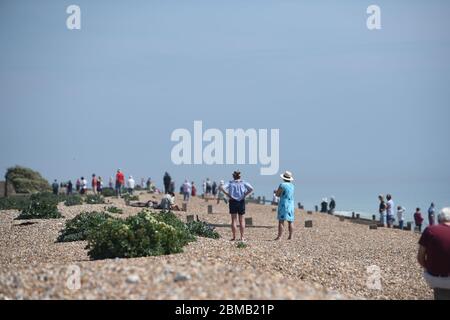Littlehampton UK 8. Mai 2020 - Menschen versammeln sich am Strand von Ferring bei Worthing, um zu beobachten, wie die spitfire in der Ferne vorbeifliegen, um an den Jahrestag des VE-Tages während der Sperrbeschränkungen der COVID-19-Pandemie zu erinnern. Es ist 75 Jahre her, dass der Sieg in Europa über die Deutschen während des Zweiten Weltkriegs verkündet wurde : Credit Simon Dack / Alamy Live News Stockfoto