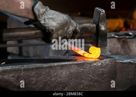 Ein Schmied schlägt auf einem Amboss rotes heißes Metall ein. Stockfoto