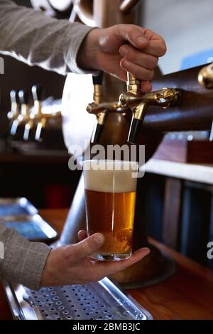 Kaukasischer Mann, der ein Pint Bier in einer Brauerei serviert Stockfoto