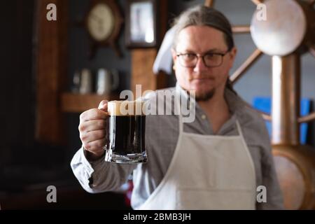 Kaukasischer Mann, der ein Pint Bier in einer Brauerei hält Stockfoto