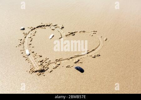 Herz, geschrieben auf nassem Strandsand mit Kopierraum unten in einem konzeptuellen Bild Stockfoto