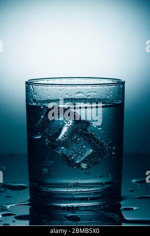 Glas Mineralwasser mit Eis. Dramatisches Licht Stockfoto
