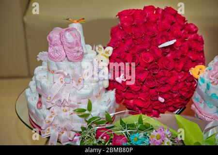 Ein Blumenstrauß von hundert roten Rosen. Großer Strauß von hundert großen roten Rosen Blumen.Rosa Kinderschuhe. Kuchen aus Windel in einem Stockfoto