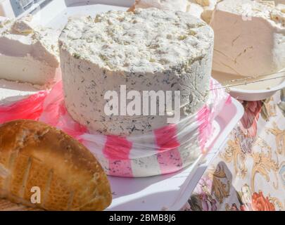 Ein Stück Käse mit Dill und Gewürzen, zum Verkauf auf der Theke, während des Food Festivals. Traditionelle Milchprodukte aus frischen Kuh oder Ziege mi Stockfoto