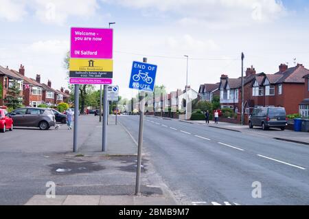 Schild mit der Aufgabe 'Willkommen - Sie sind jetzt IN Salford' aus Kearsley, England. Die Radroute endet und es gibt eine Spaltung in der Pflaster. bolton rat. Stockfoto