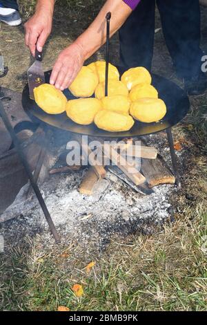 In der Mitte stehen Polenta- und Käsebälle, genannt Bulz, ein traditionelles rumänisches Gericht. Polenta und Käse auf einem Grill draußen braten, mit Schafen Stockfoto