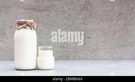 Frische Milch in einer Flasche auf grauem Hintergrund. Kefir, Milch oder türkischer Ayran trinken in einer Glasflasche. Konzept des Weltmilchtages. Platz für Text. Stockfoto