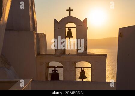 Sonnenuntergang über einem weißgetünchten Glockenturm in der Villa von Oia, Santorini, Griechenland Stockfoto