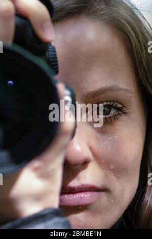 Eine Reporterin weint während der Dreharbeiten der Tragödie. Ein Blick auf die Kamera und Tränen auf dem Gesicht einer schönen jungen Fotografin. Portrait Close-U Stockfoto