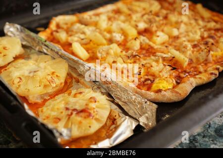 Hühnerfilet mit Ananas auf Folie und hausgemachter hawaianischer Pizza. Einfache hausgemachte Rezepte mit Ananas Stockfoto