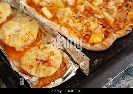 Hühnerfilet mit Ananas auf Folie und hausgemachter hawaianischer Pizza. Einfache hausgemachte Rezepte mit Ananas Stockfoto