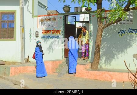 Anganwadi-Arbeiter, die eine schützende Gesichtsmaske tragen, interagiert während einer Tür-zu-Tür-Umfrage mit einem Mädchen, um die Ausbreitung des neuartigen Coronavirus im Dorf Ganeshpura in Beawar zu überprüfen. (Foto von Sumit Saraswat/Pacific Press) Stockfoto