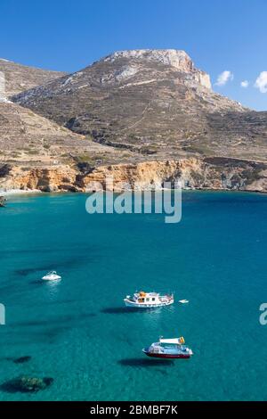 Landschaftsansicht von Booten auf dem Wasser in der Nähe der Küste am Livadaki Strand, Folegandros, Kykladen Inseln, Griechenland Stockfoto