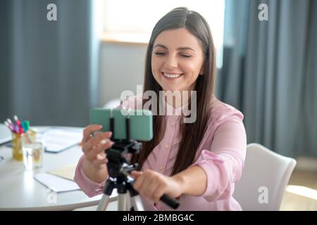 Dunkelhaarige junge Frau in einer rosa Bluse immer Kamera bereit Stockfoto