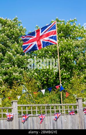 Ashford, Kent, Großbritannien. Mai 2020. Mitglieder der Gemeinde im Dorf Hamstreet in der Nähe von Ashford in Kent kommen zusammen, um den Tag VE an seinem 75. Jahrestag mit einer Teeparty vor ihrem Vorgarten zu gedenken. Union Jack Flagge an einem sonnigen Tag fliegen. ©Paul Lawrenson 2020, Foto: Paul Lawrenson/Alamy Live News Stockfoto