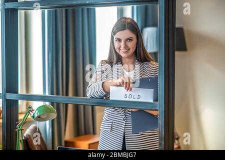 Dunkelhaarige hübsche junge Frau lächelt und sieht zufrieden aus Stockfoto