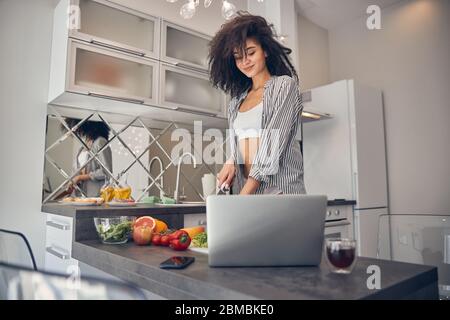 Schöne dunkelhaarige Mädchen nach einem Online-Rezept Stockfoto