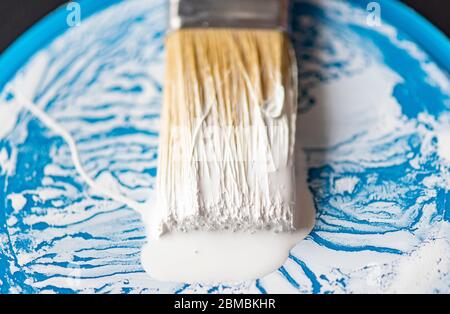 Nahbemalung Pinsel oder Pinsel mit weißer Farbe auf der Oberfläche der Borsten und blauen Zinn, Dose Stockfoto